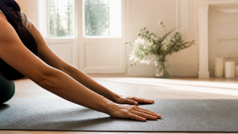 Mains posées doucement sur un tapis de yoga dans un intérieur calme et lumineux, symbolisant le recentrage et l'apaisement après un soin énergétique