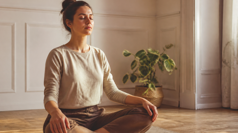 Personne assise en méditation paisible dans un intérieur calme, mains posées sur les genoux, lumière douce naturelle
